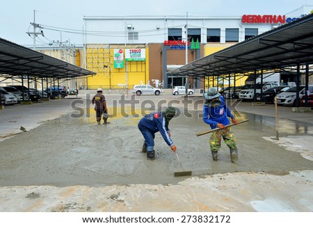 MAHASARAKHAM - OCTOBER 8 : Masonry workers repair concrete parking floor at Sermthai complex on October 8, 2014 in Mahasarakham, Thailand.