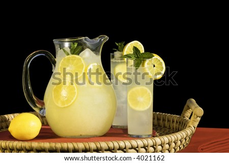 Pitcher And Glasses Of Cold Fresh Squeezed Lemonade On Rattan Tray ~ Isolated On Black