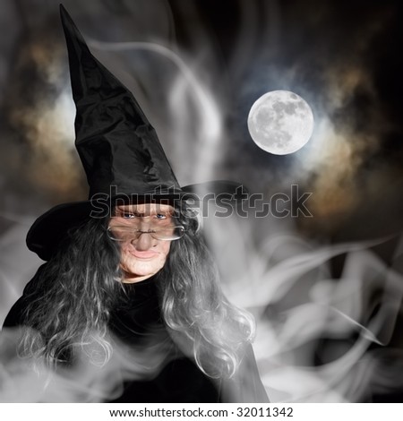 Elderly Witch With Black Hat Casting Spells, Full Moon And Cloudy Night Background