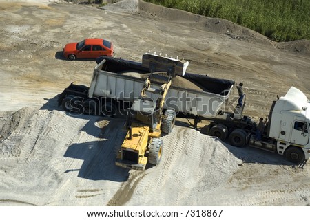 a Construction vehicle loading sand onto a cargo truck viewed from above
