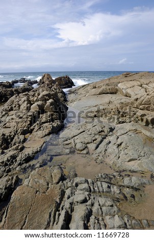 Dramatic colorful image of rocks leading to the ocean. Stormy clouds in the background.