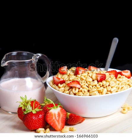 Fresh corn flakes with strawberries close up isolated on black