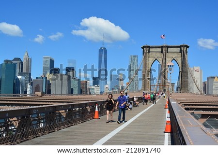 New York City, USA - August 24, 2014: People walking across the Brooklyn Bridge with the Lower Manhattan skyline in the background in New York City.