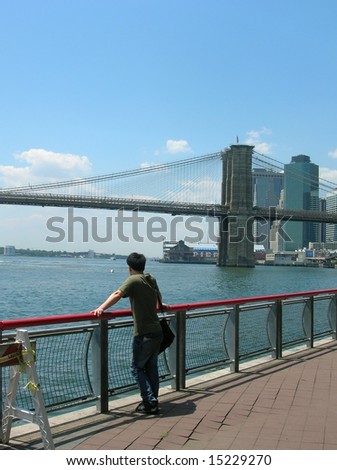 Man on a path near the East River and Brooklyn Bridge.