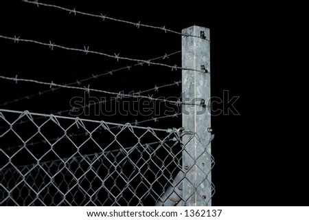 A barb-wired fence in the night.