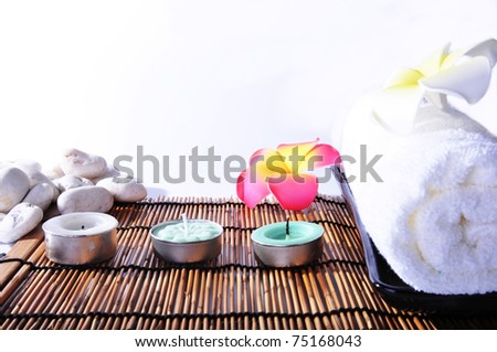 Three candles and one white towels on bamboo mat