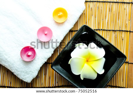 Three candles on white towel and plumeria on the plate
