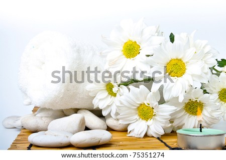 Simple white daisy, towel and candle on bamboo mat with isolated white background