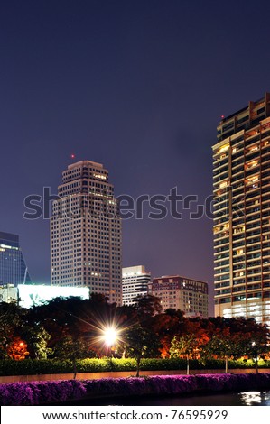 buildings with a green space and lake by night.bangkok