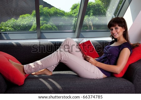young woman laying on couch reading a book 6780