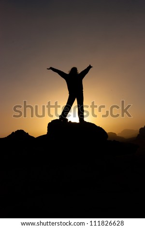 A person in silhouette against a desert sunrise