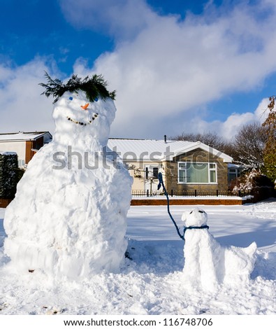 Snowman with a pet snow dog under a blue sky on a crisp winter\'s day