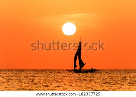 Traditional sailing boat and a tropical sunset on a calm ocean
