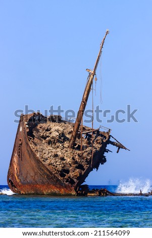 Waves breaking on an old, rusting ship wreck abandoned on a coral reef