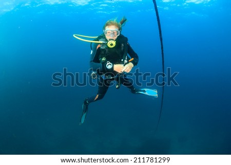 A SCUBA diver hovers next to a line in blue water
