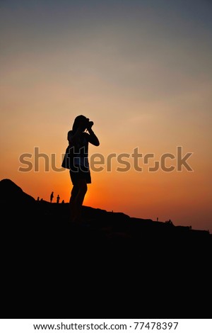 Woman taking a photography silhouette in sunset background