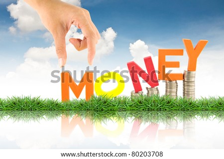 Hand pick up money word, against blue sky background