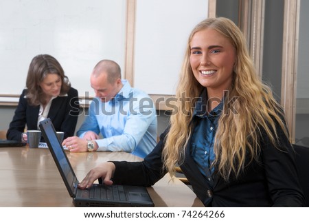 Young, stunning professional businesswoman smiling into the camera at an office board meeting