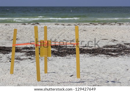 Four yellow sticks with orange tape connecting them all is surrounding a place in the sand on the Gulf coast beach where wild turtles have laid their eggs on Lido Key in Sarasota, Florida.