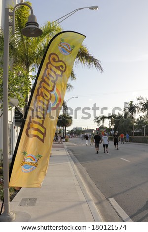 WILTON MANORS, FLORIDA - JUNE 22, 2013: Yellow flag banner with Stonewall and summer pride name, rainbows, graphics at the gay pride celebration in Wilton Manors, Florida with people on Wilton Drive.