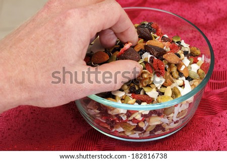 Healthy vegan trail mix of dry fruits and nuts of strawberry, blueberry, black currants, dates, pumpkin seeds, pine nuts, almonds, coconut, walnuts, pistachio, raisins, sesame seeds, and pine nuts.
