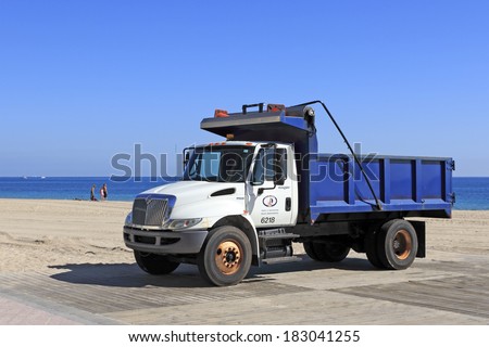 FORT LAUDERDALE, FLORIDA - JANUARY 28, 2014: Parked on a wooden platform just north of Fort Lauderdale Beach Park a white and blue dump truck sits ready for work with a view of the Atlantic ocean.