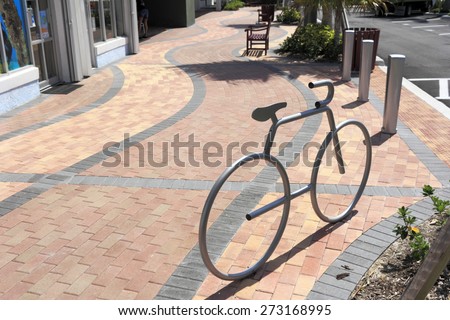 LAUDERDALE-BY-THE-SEA, FL, USA - APRIL 7, 2014: One silver metal bike rack in the shape of a bike mounted on a brick sidewalk on a sunny day. A silver bike rack in bicycle shape on a brick sidewalk