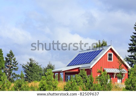 Bright red building with solar panels on the metal rooftop on a mostly sunny summer day in a public park.
