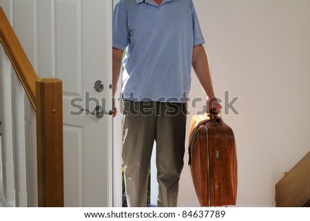 Man arriving from business travel inside the front door of his home.