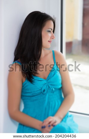 Beautiful pensive brunette looking through window