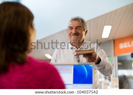 Portrait of young woman and happy old retired man returning book to library