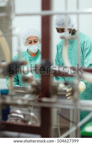 Laboratory technicians at work in medical plant with machinery and computers