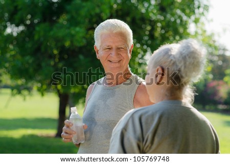 Senior people, old man and woman talking and drinking water after exercising in park