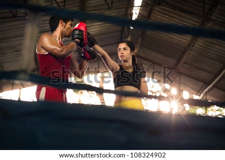 Young woman exercising with trainer at boxe and self defense lesson. Copy space