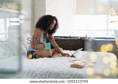 African american college student doing homework in bed at home, young black woman preparing school test in bedroom with laptop pc