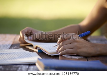 Young women and education, close up of hands of girl studying for college exam in park. Side view, copy space