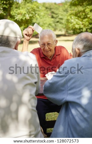 Active Retirement, Old People And Seniors Free Time, Group Of Three Elderly Men Having Fun And Playing Cards Game At Park. Waist Up