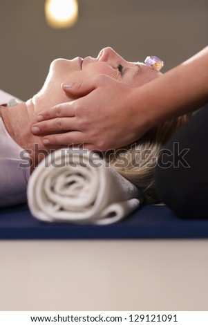 Reiki therapy with girl working as spirit healer, arranging crystals and gemstones on female client for treatment