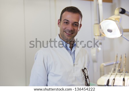 Dental care and hygiene, portrait of adult caucasian dentist at work and smiling at camera
