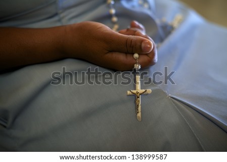 People and religion, catholic sister praying in church and holding cross in hands. With model release