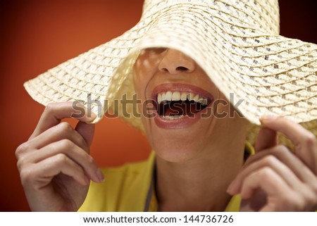 mid adult woman with straw hat smiling and having fun on red background