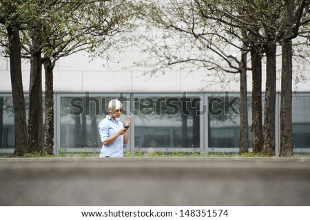 young businesswoman smoking cigarette during break out of office building. Wide shot, copy space