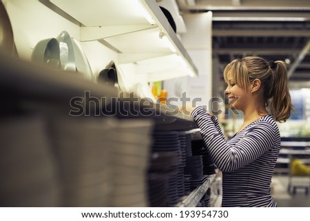 young hispanic woman shopping for furniture, glasses, dishes and home decor in store
