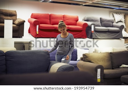 young hispanic woman shopping for furniture, sofa and home decor in store