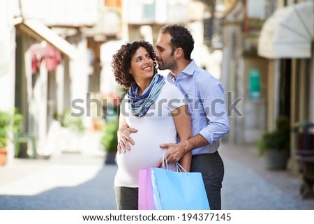 Portrait of happy people with husband and pregnant wife shopping and having fun in italian city street