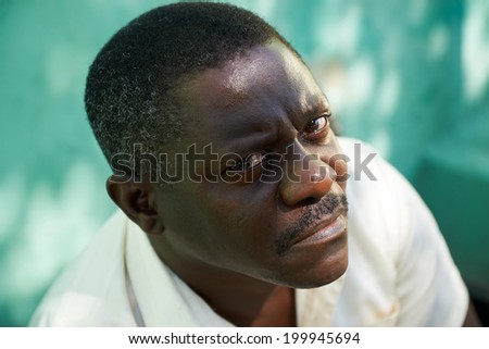 Portrait of mid aged african american man sitting in park and looking at camera with sad expression