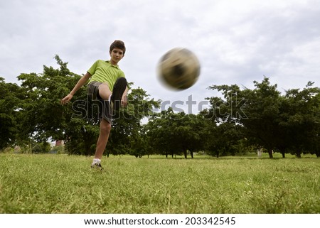 Children playing soccer game in park, with copy space on grass and focus on football ball