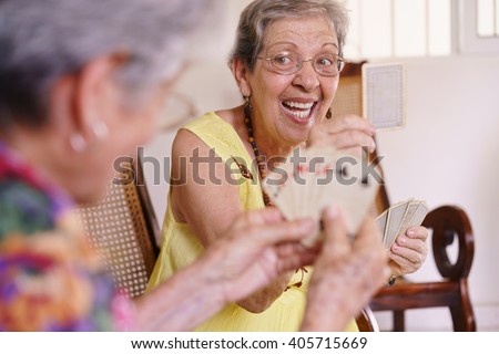 Old people in geriatric hospice: group of senior women playing cards and having fun together. An aged lady wins the game and shows a card to her rival