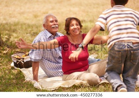 Old people, senior couple, elderly man and woman. Outdoor family having fun with happy grandpa and grandma hugging boy at picnic in park.
