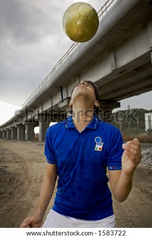 guy playing football under a bridge